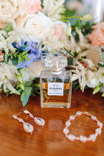 Image of Chanel No 5 perfume with crystal earrings and bracelet on a table with flowers in the backdrop